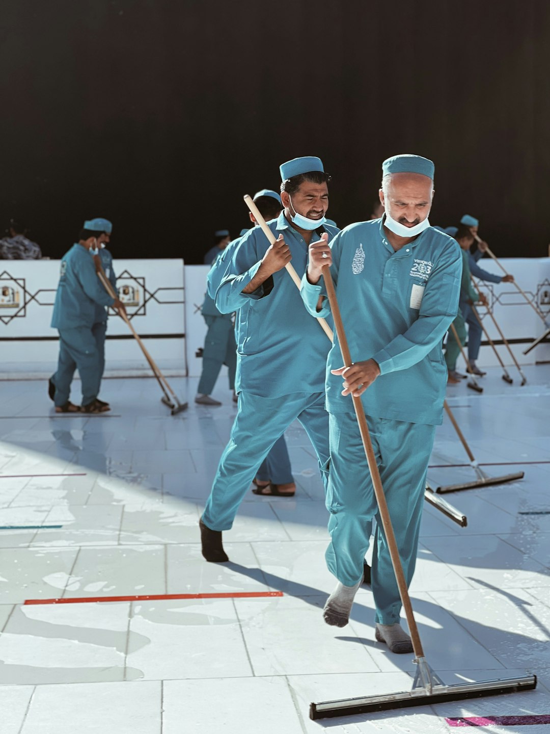 a-group-of-men-in-blue-uniforms-with-brooms-98wolbjsbyc